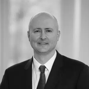A black and white image of David McCoy, president of Integrity Federal Services. He is wearing a business suit and smiling.